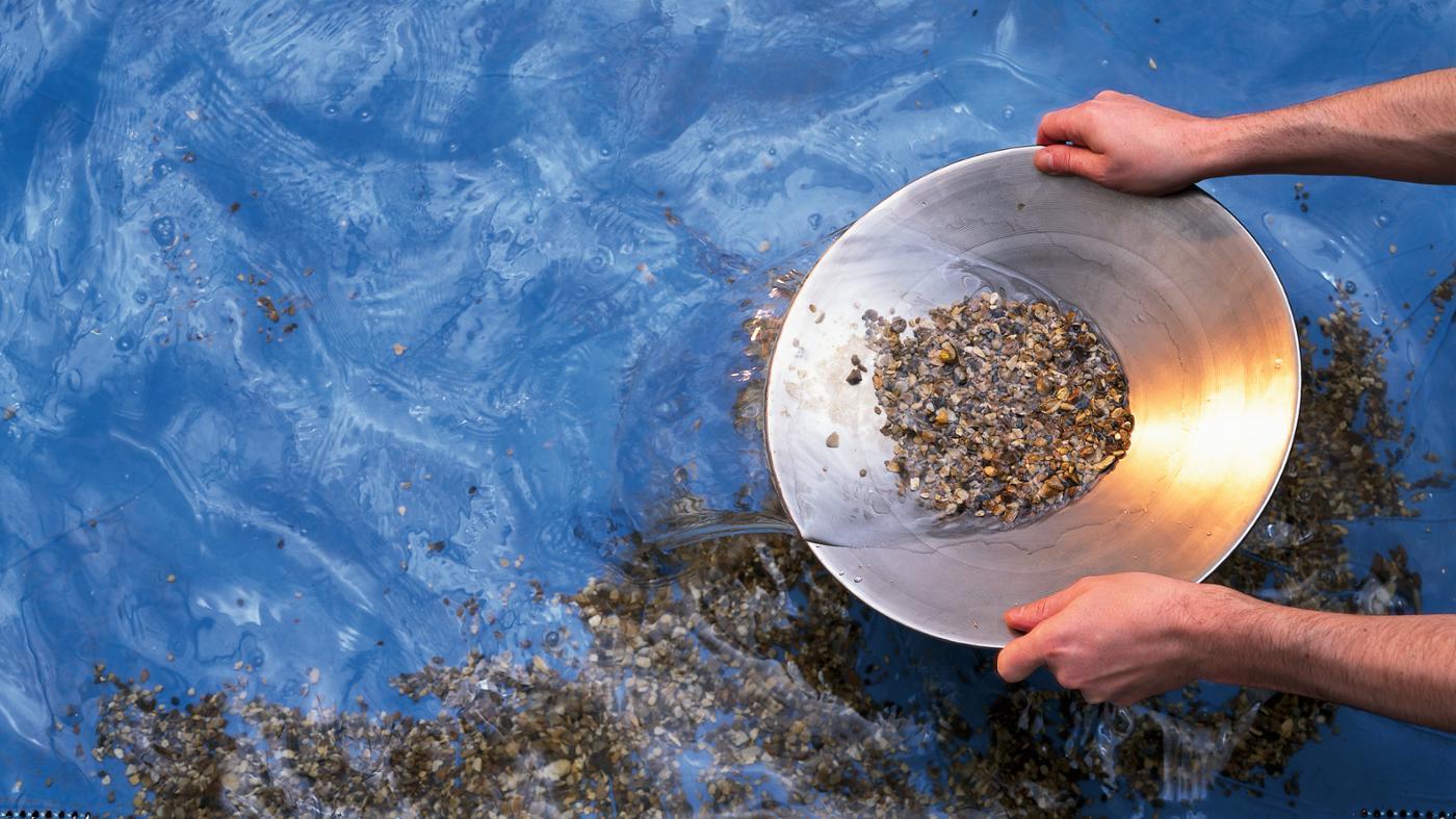 Pan being pulled from water with gold pieces